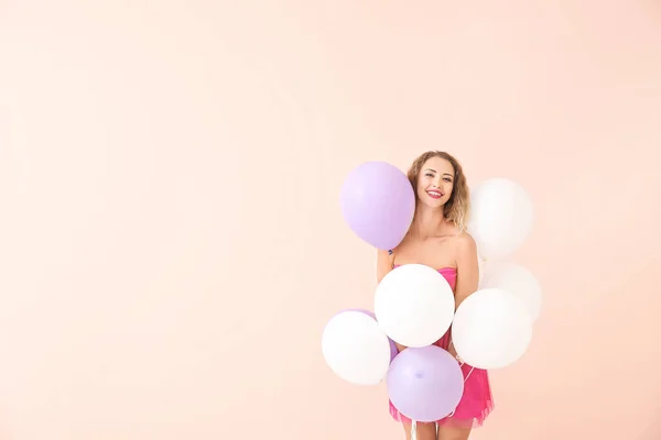 Bella giovane donna con palloncini su sfondo di colore — Foto Stock