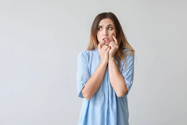 Portrait of worried young woman on light background — Stock Photo, Image