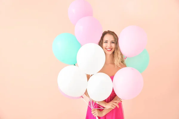 Piękna młoda kobieta z balonami na tle koloru — Zdjęcie stockowe