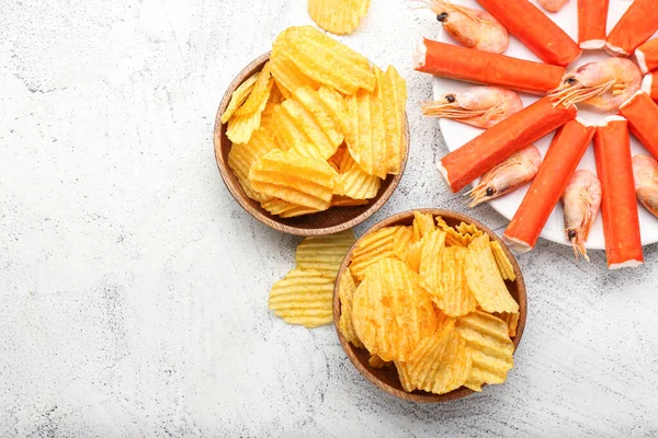 Bowls with tasty potato chips and crab sticks on light background — Stock Photo, Image