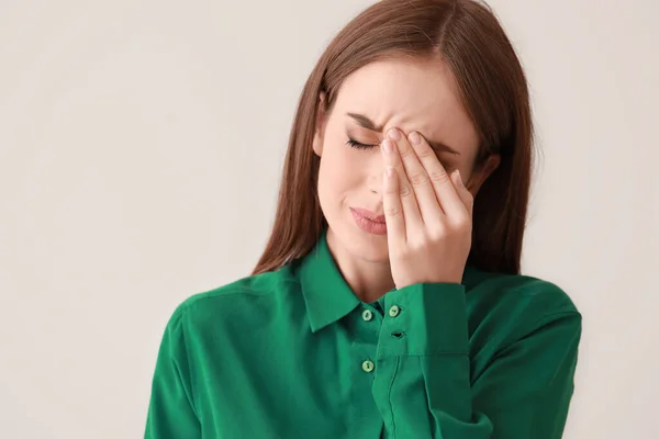 Genç kadın ışık arka plan üzerinde baş ağrısı muzdarip — Stok fotoğraf