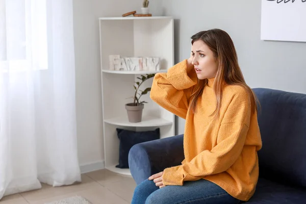 Retrato de una joven preocupada sentada en un sofá en casa —  Fotos de Stock