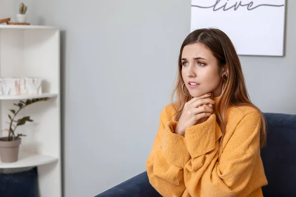 Retrato de una joven preocupada sentada en un sofá en casa —  Fotos de Stock