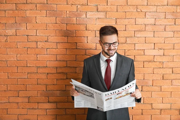 Hombre de negocios guapo con periódico contra pared de ladrillo — Foto de Stock