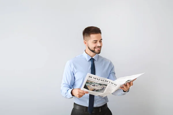 Hombre de negocios guapo con periódico sobre fondo claro — Foto de Stock