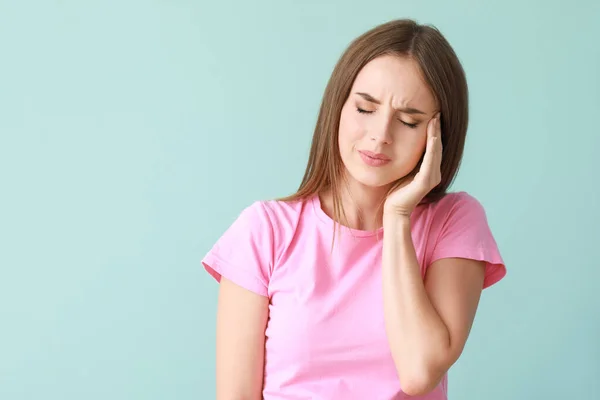 Young woman suffering from headache on color background — Stock Photo, Image