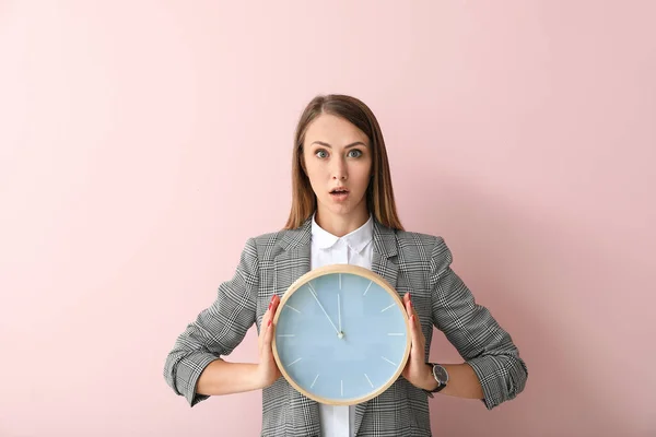 Stressed young businesswoman with clock on color background — Stock Photo, Image