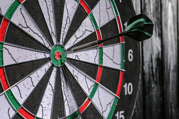 Dartboard with hit bullseye hanging on wall, closeup — Stock Photo, Image