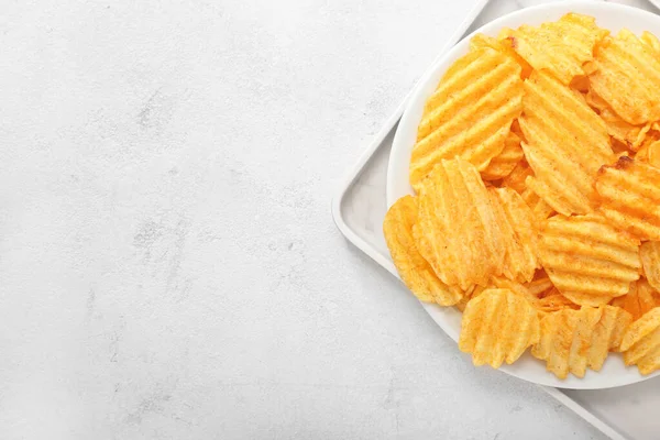 Hafif arka planda lezzetli patates cipsi tabağı.