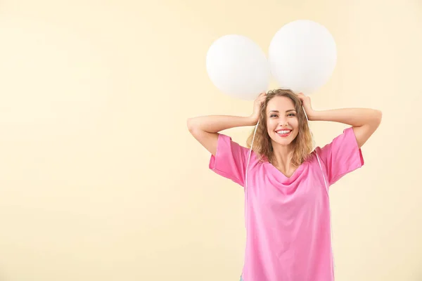 Funny young woman with balloons on color background — ストック写真