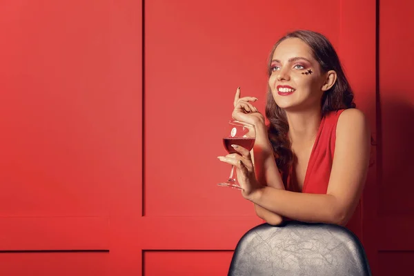 Mulher jovem na moda com copo de vinho perto da parede de cor — Fotografia de Stock