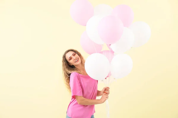 Schöne junge Frau mit Luftballons auf farbigem Hintergrund — Stockfoto