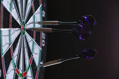 Karanlık arka planda dartları olan dart tahtası, yakın plan görünümü