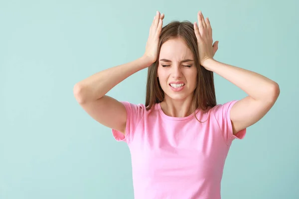 Junge Frau leidet unter Kopfschmerzen auf farbigem Hintergrund — Stockfoto