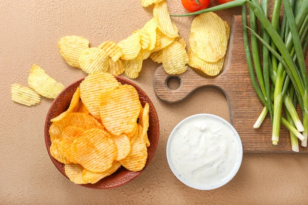 Tasty potato chips with sour cream and green onion on color background — Stock Photo, Image