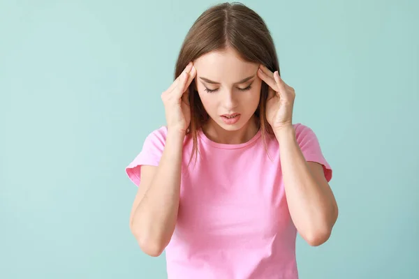Genç kadın renk arka plan üzerinde baş ağrısı muzdarip — Stok fotoğraf