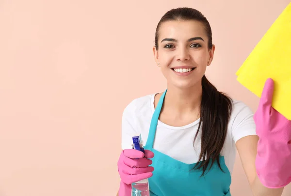 Vrouwelijke conciërge met schoonmaak benodigdheden op kleur achtergrond — Stockfoto