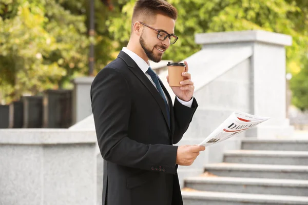 Hombre de negocios guapo con periódico y café al aire libre — Foto de Stock