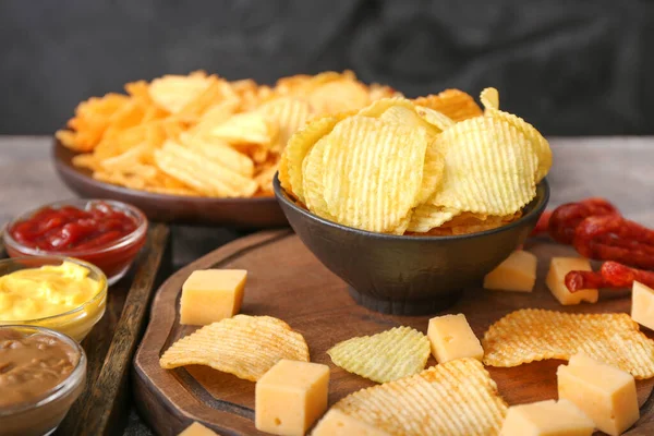 Tigela com saborosas batatas fritas, queijo e molhos na mesa — Fotografia de Stock