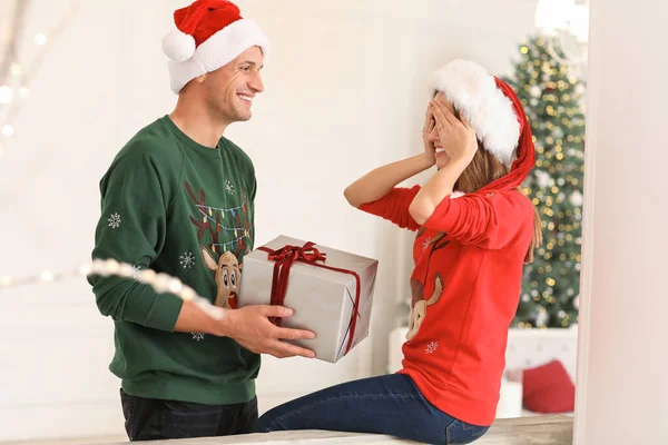 Jovem feliz dando presente de Natal para sua namorada em casa — Fotografia de Stock