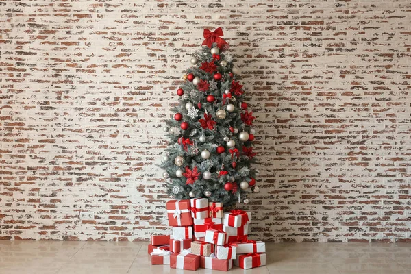 Gyönyörű díszített karácsonyfa ajándékokkal közelében fehér fal — Stock Fotó