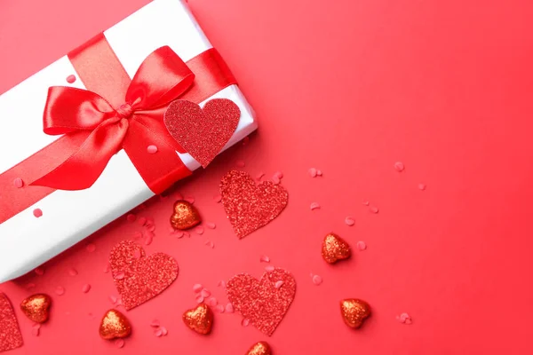 Scatola regalo per San Valentino e cuori rossi su sfondo a colori — Foto Stock