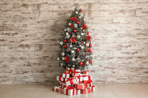 Beautiful decorated Christmas tree with gifts near white wall — Stock Photo, Image