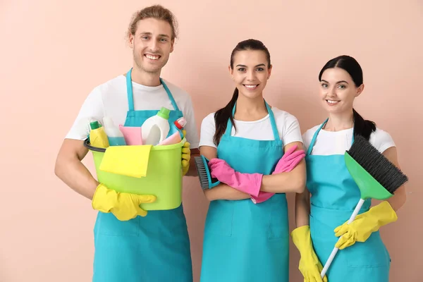 Team di custodi con prodotti per la pulizia su sfondo a colori — Foto Stock