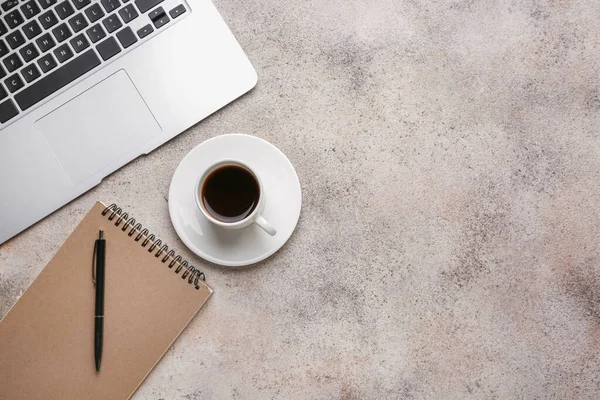 Cup of hot coffee with laptop and stationery on grey background — Stock Photo, Image