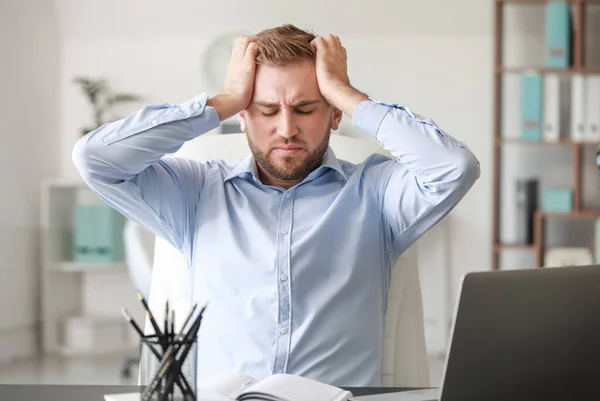 Young man suffering from headache in office — Stock Photo, Image