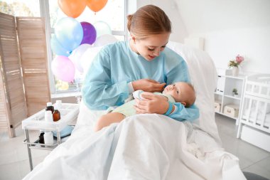 Young mother with newborn baby in maternity hospital clipart