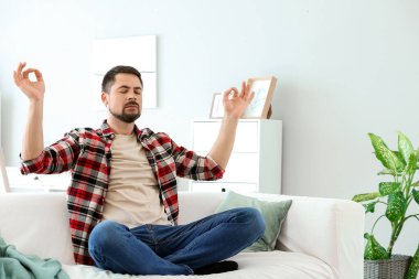 Evde meditasyon yapan yakışıklı bir adam.