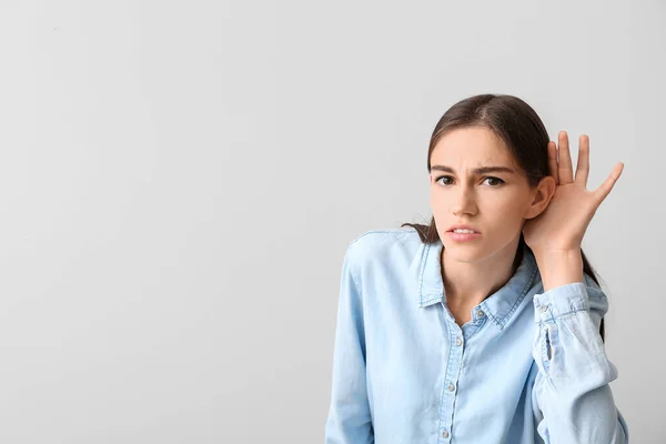 Junge Frau mit Hörproblemen auf hellem Hintergrund — Stockfoto