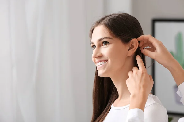 Donna che mette l'apparecchio acustico nell'orecchio della ragazza a casa — Foto Stock