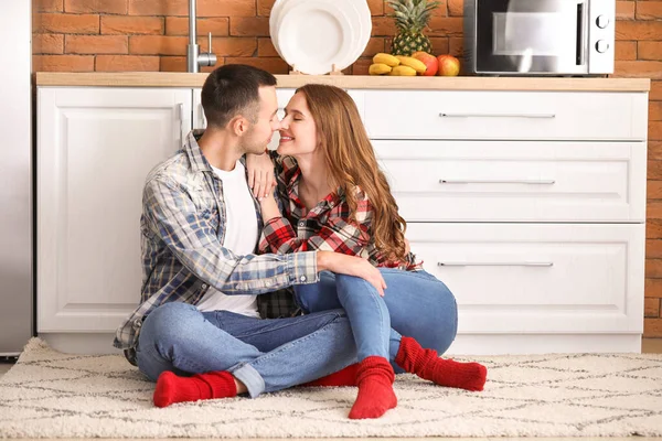 Feliz jovem casal sentado no chão na cozinha — Fotografia de Stock