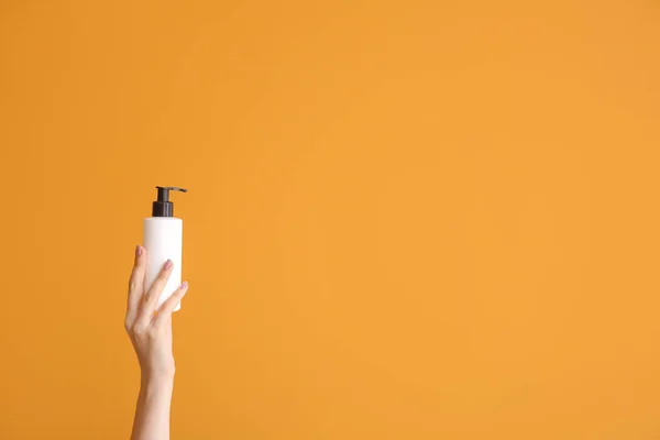 Γυναικείο χέρι με καλλυντικό προϊόν σε μπουκάλι στο φόντο χρώμα — Φωτογραφία Αρχείου