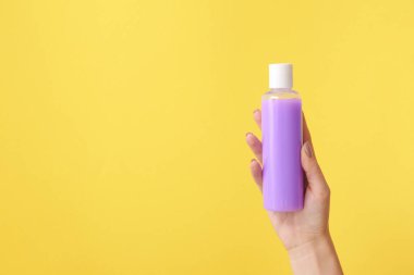 Renkli arka planda kozmetik ürünü olan bir kadın el.