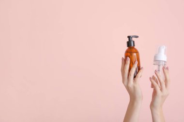 Farklı kozmetik ürünlere sahip kadın elleri renkli arka planda şişelerde