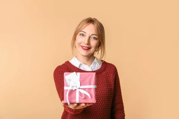 Beautiful mature woman with gift box on color background — Stock Photo, Image