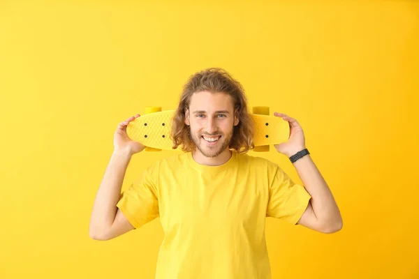 Ritratto di uomo felice con skateboard su sfondo a colori — Foto Stock