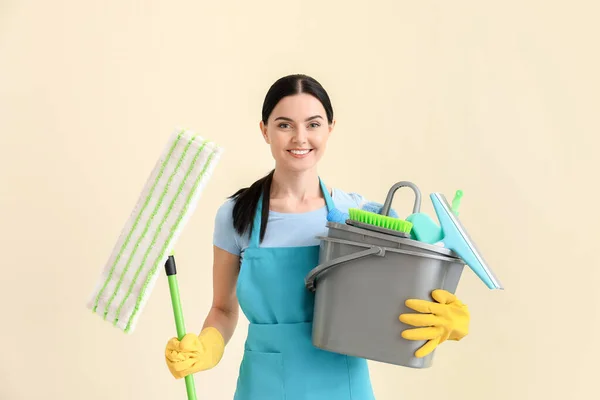 Vrouwelijke conciërge met schoonmaakmiddelen op lichte achtergrond — Stockfoto