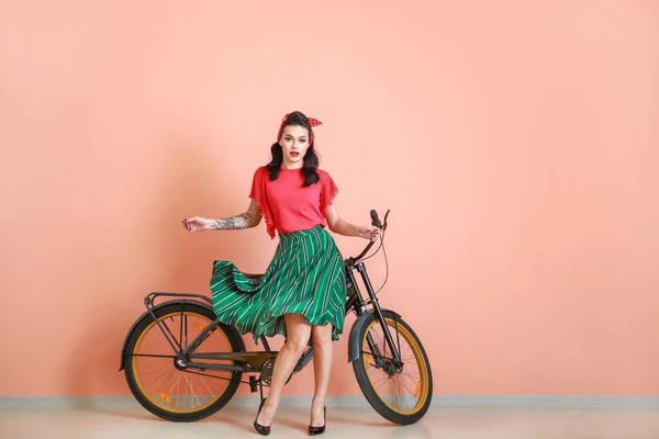 Retrato de bela mulher tatuada pin-up com bicicleta perto da parede de cor — Fotografia de Stock