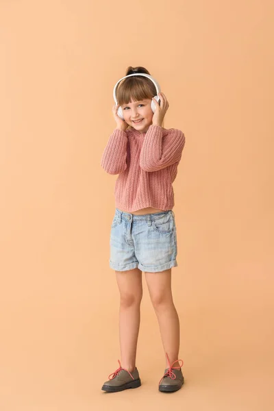 Мила дівчинка слухає музику на кольоровому фоні — стокове фото