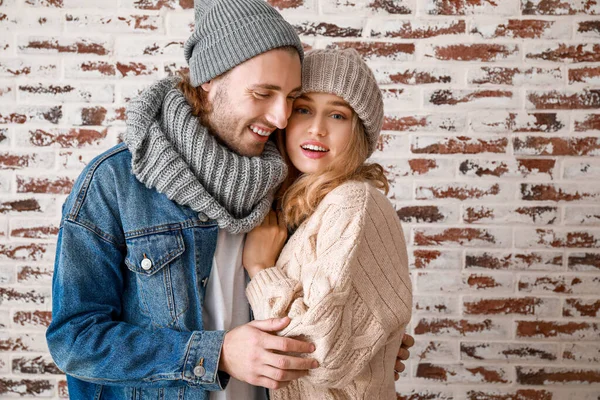 Ευτυχισμένο νεαρό ζευγάρι με ζεστά φθινοπωρινά ρούχα κοντά σε τοίχο — Φωτογραφία Αρχείου