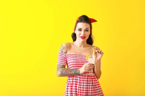 Portrait of beautiful tattooed pin-up woman with cocktail on color background — Stock Photo, Image