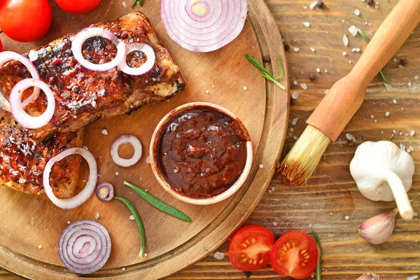 Tasty grilled meat with barbecue sauce, vegetables and spices on table — Stock Photo, Image
