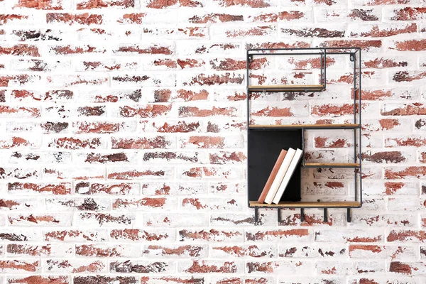 Shelf with books hanging on brick wall — Stock Photo, Image