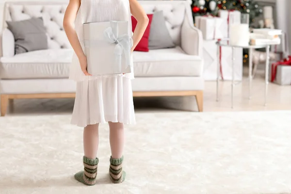 Κοριτσάκι με χριστουγεννιάτικο δώρο πίσω από την πλάτη της στο σπίτι — Φωτογραφία Αρχείου