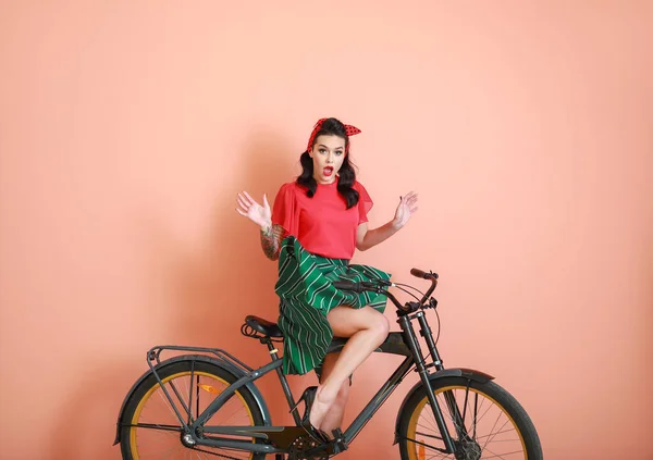 Portrait de femme pin-up tatouée surprise à vélo sur fond de couleur — Photo