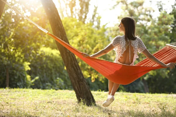 Happy young woman sitting in hammock outdoors — Stock Photo, Image